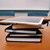 Mehrere Bücher mit einem Tablet liegen auf dem Tisch übereinander