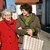 Frau geht mit Senioren im Arm zum Einkaufen