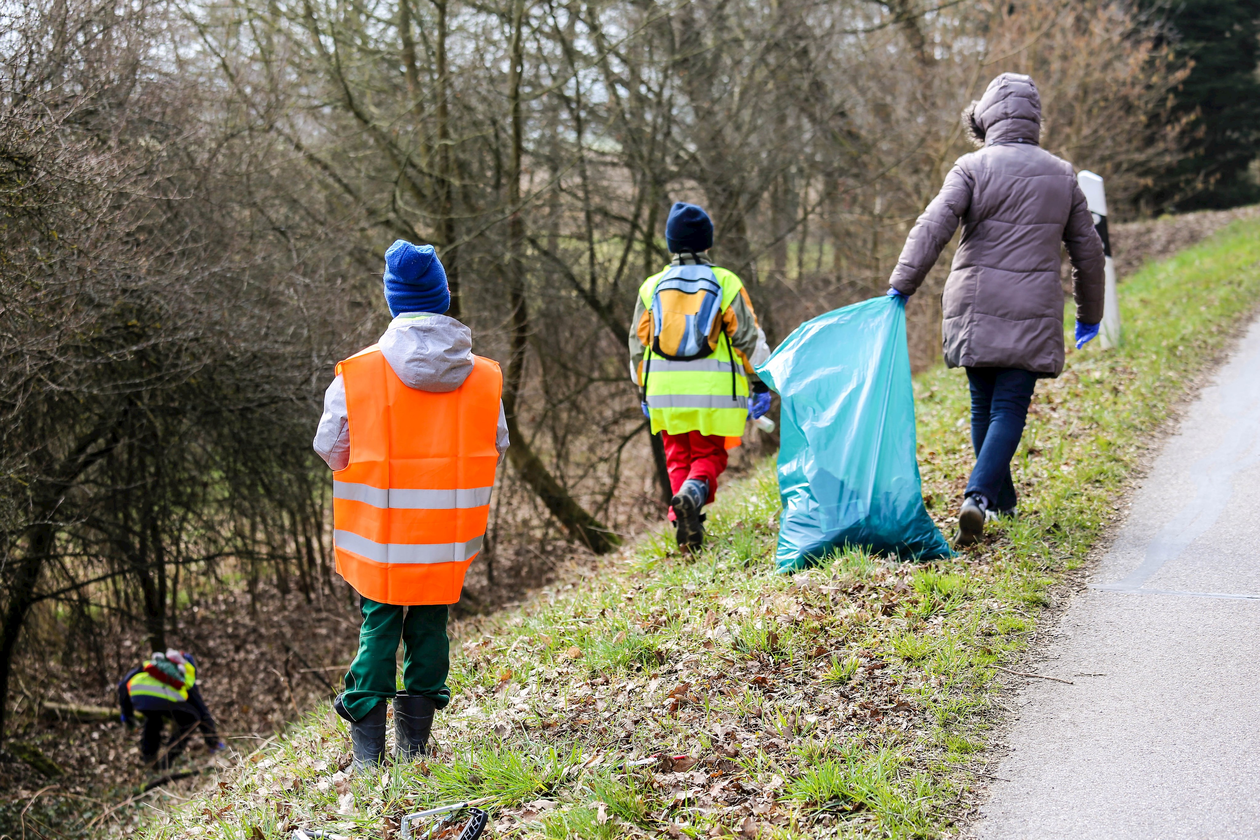 Eine Frau mit zwei Kindern sammeln Müll am Straßenrand