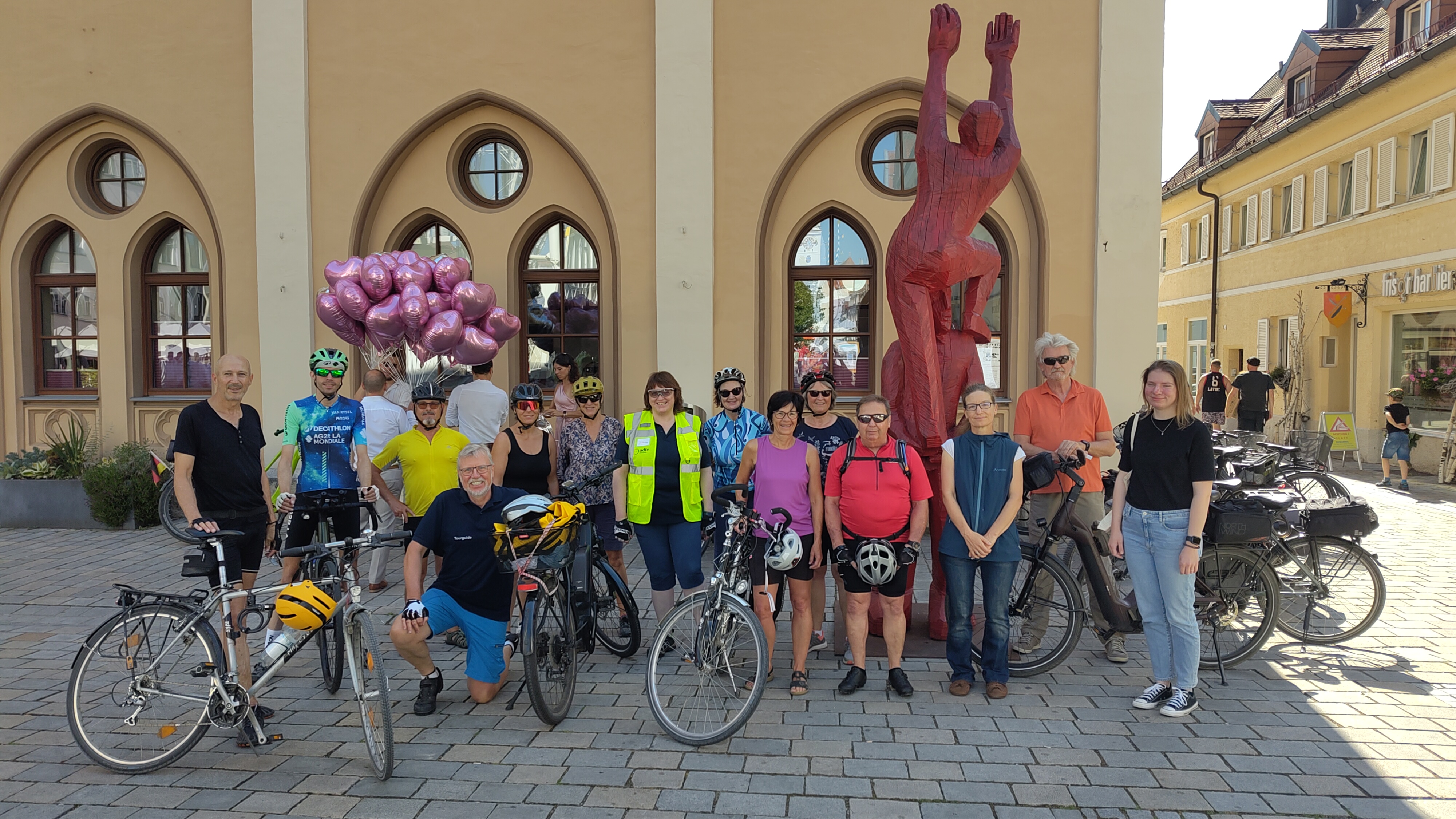 mehrere Personen stehen mit Fahrrädern in einer Gruppe nebeneinander