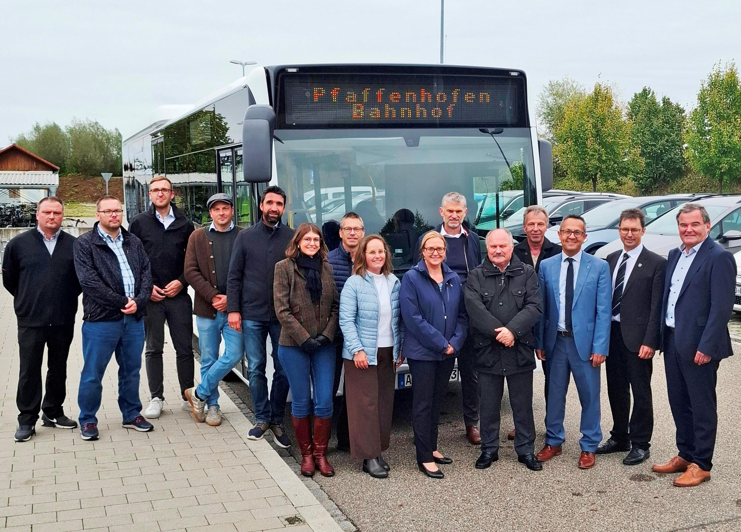 mehrere Personen stehen nebeneinander vor einem Bus