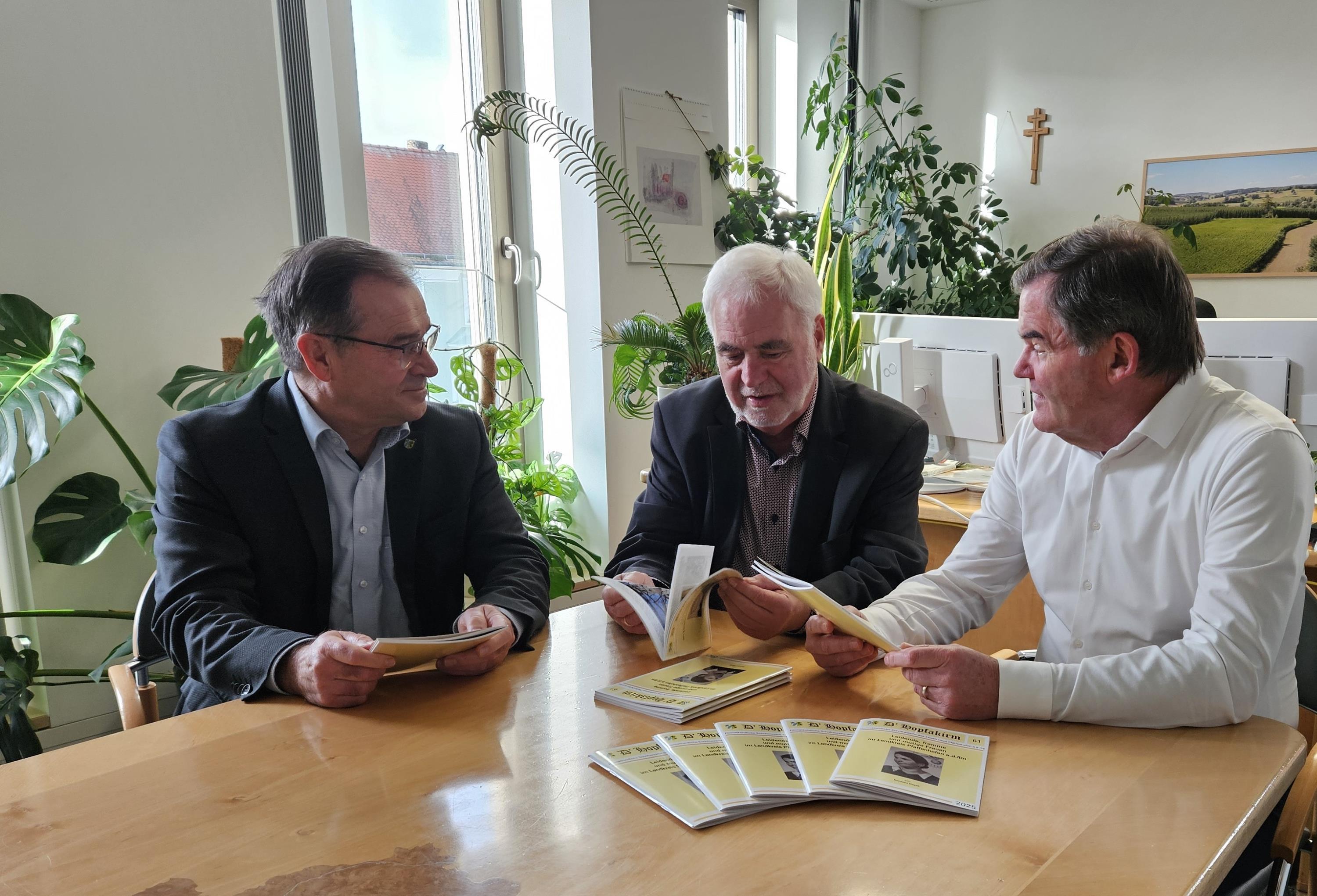 drei Personen sitzen an einem Tisch