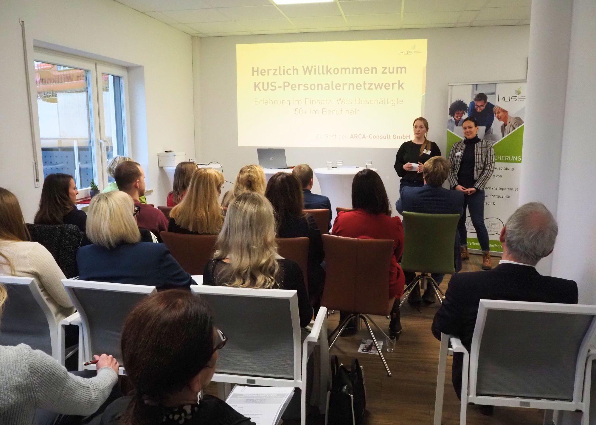 mehrere Personen sitzen bei einem Vortrag