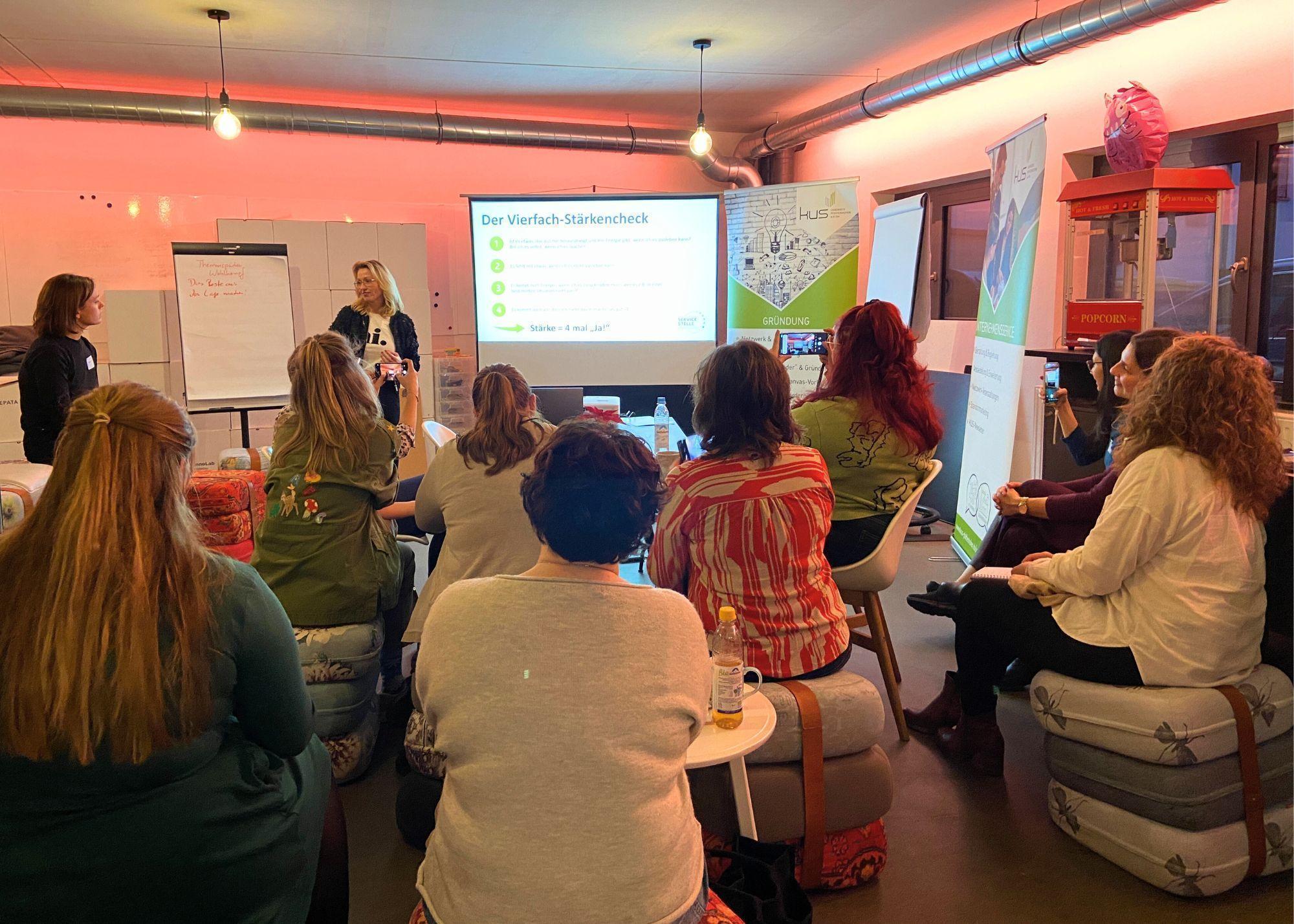 mehrere Personen sitzen bei einem Vortrag