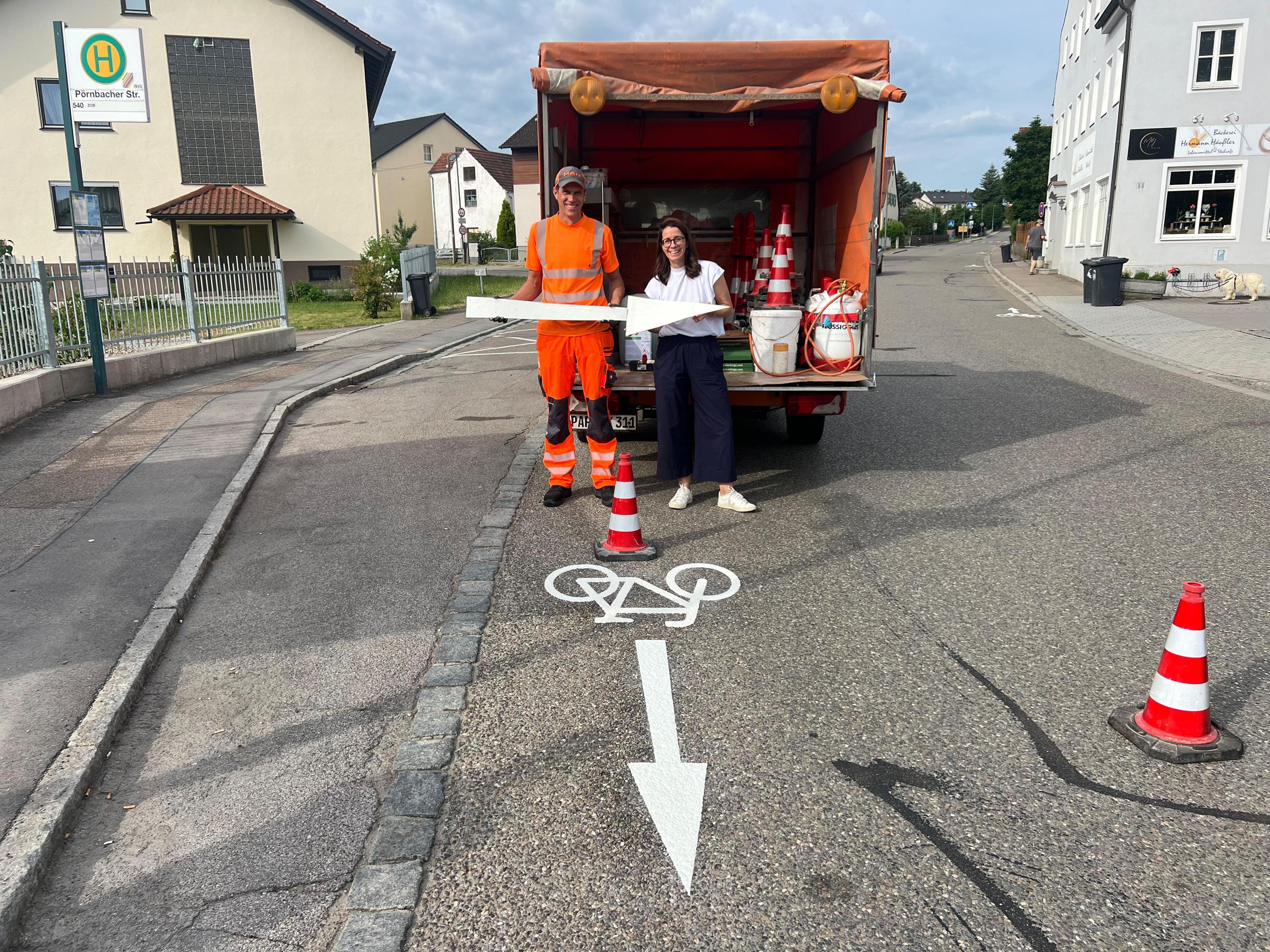 zwei Personen stehen vor einem Auto auf einer Straße