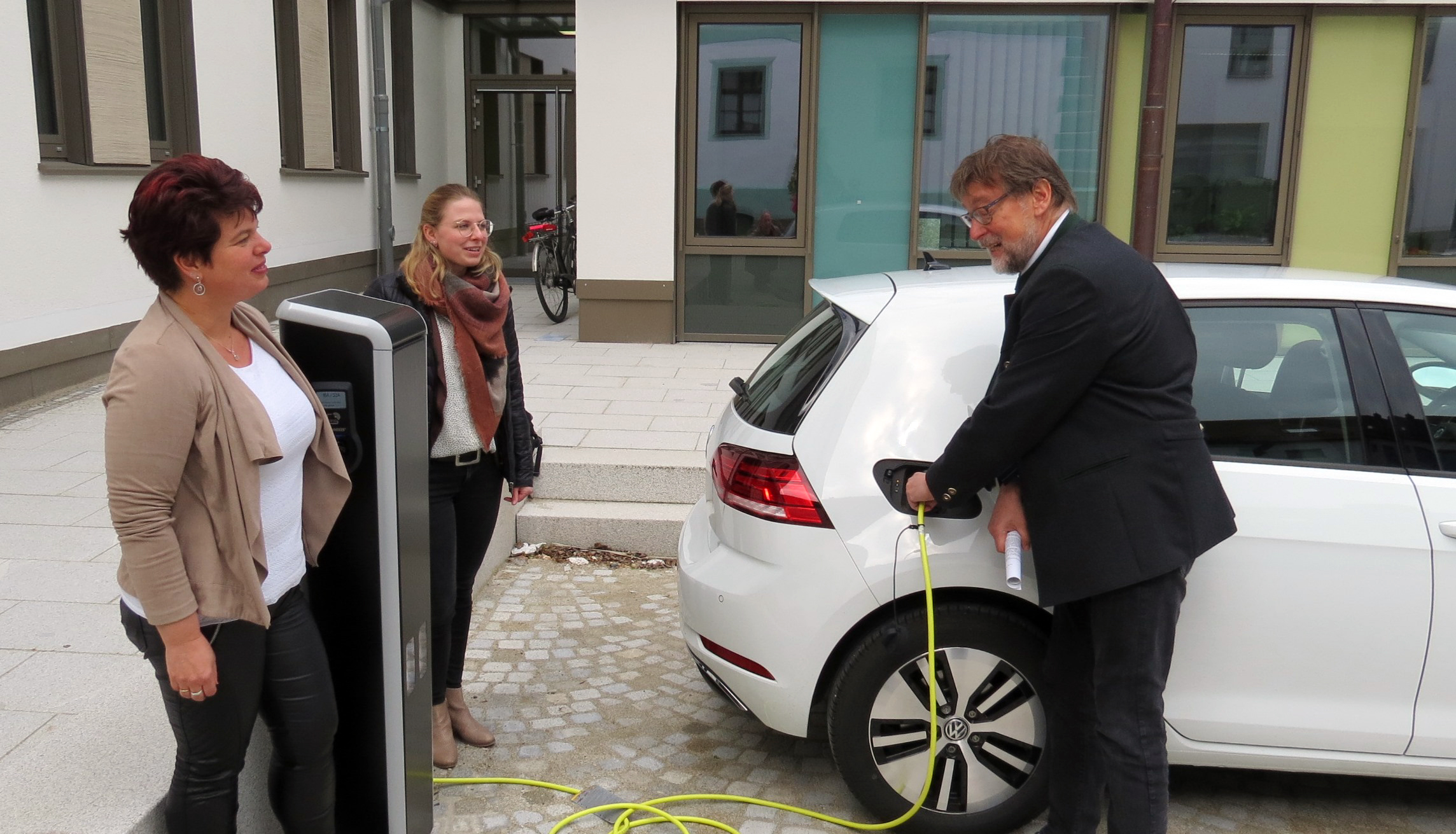 v.r.n.l.: Landrat Martin Wolf, Landratsamtsmitarbeiterin Sandra Schmeller mit ihrem E-Auto sowie Monika Meier von der Servicestelle des Landratsamts beim offiziellen ersten Ladevorgang Leider haben wir keinen Alternativtext zu diesem Bild, aber wir arbeiten daran.